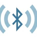A clean, wide-angle digital illustration showing a modern workspace with a smartphone, laptop, wireless earbuds, and smartwatch. They are placed apart but visually connected by subtle blue dotted lines, representing how Bluetooth works by sending wireless signals between devices for seamless connectivity. The composition is minimal, calm, and tech-friendly, with soft lighting and a neutral background.